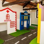 A play area at Leafield House Nursery featuring a house, a hospital, and a police station for imaginative play.