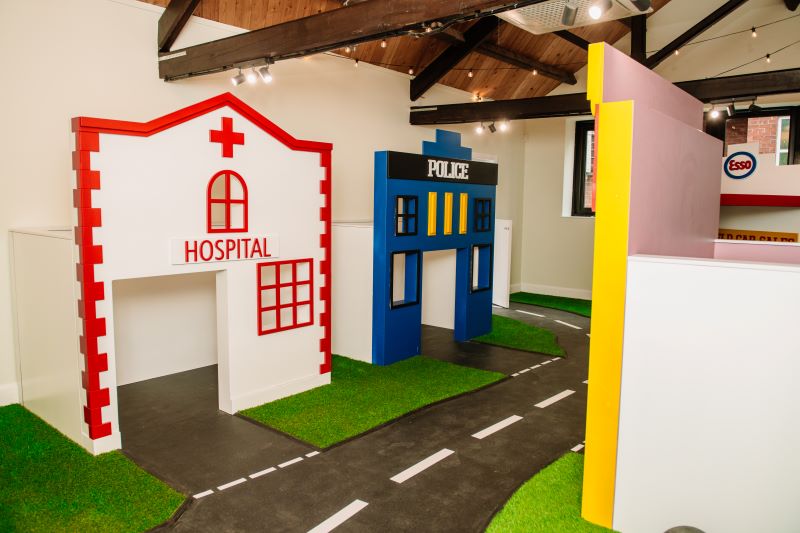A play area at Leafield House Nursery featuring a house, a hospital, and a police station for imaginative play.